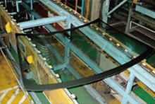 The production process of automotive glass: Where glass is formed into the prescribed shape by applying heat; the black parts are where ceramic is sintered on.