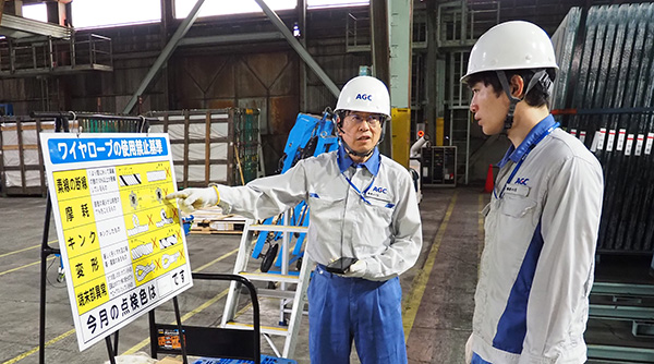 横浜テクニカルセンターの出荷倉庫にて、熟練指導者が若手に対して作業説明している画像